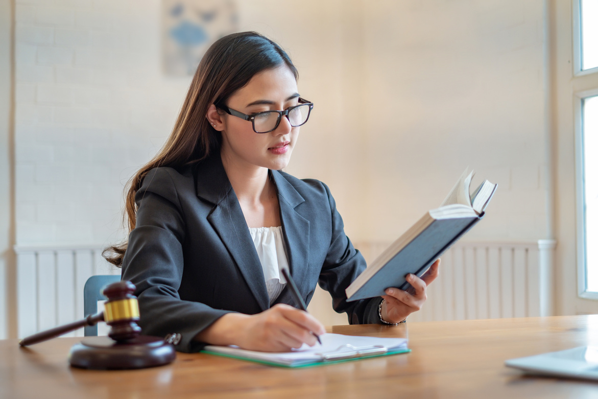 Young lawyer asian woman reading book in lawyer office.